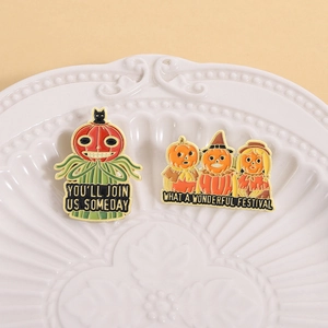 Macro shot of Halloween ghost and pumpkin enamel pins set on a vintage white plate