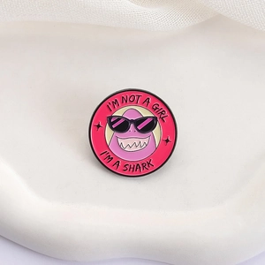 Détail du pin's requin en émail rose avec le texte I'M NOT A GIRL I'M A SHARK