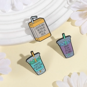 Three enamel pins set featuring beverage boxes with Spanish quotes on light background