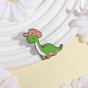 Detail shot of green dinosaur enamel pin wearing a cowboy hat and boots on floral decor