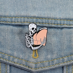Skeleton hugging human butt funny enamel pin on blue denim fabric background