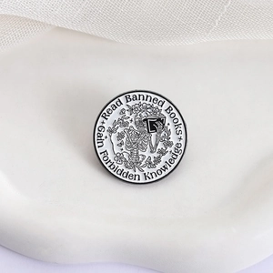 Macro shot of circular enamel pin featuring a reading skeleton and floral details