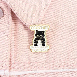 Detail of a black cat enamel pin with Crochet lettering on pink denim collar