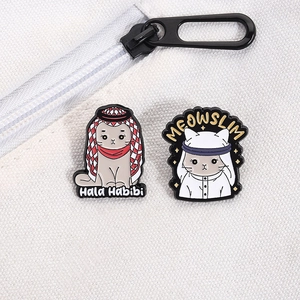 Close-up of enamel cat pins with keffiyeh design on white canvas bag texture