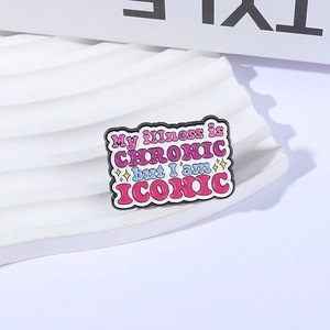 Enamel pin with My Illness is Chronic but I am Iconic slogan on white display block