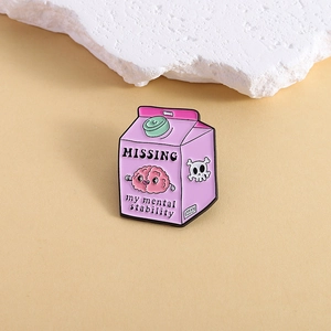 Pink milk carton enamel pin with missing mental stability text on beige stone surface