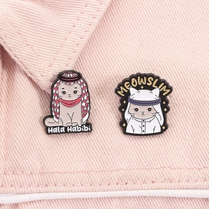 Detailed view of creative cat enamel pins with Middle Eastern cultural theme on pink fabric