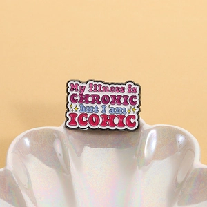 Enamel brooch with 'My illness is CHRONIC but I am ICONIC' slogan on shell background
