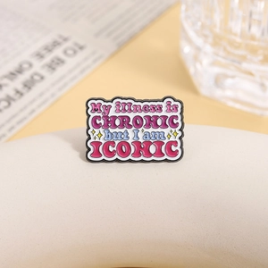 Detail of enamel pin with 'My illness is CHRONIC but I am ICONIC' quote on display stand