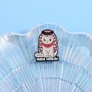 Détail d'un pin's chat musulman en émail avec texte Hala Habibi sur un plateau en verre