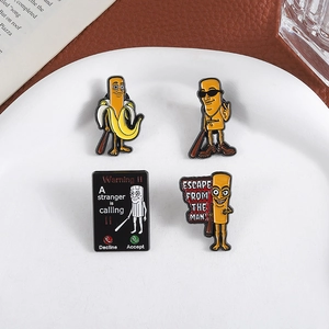 Set of four creative enamel pins with cartoon characters on a white ceramic tray