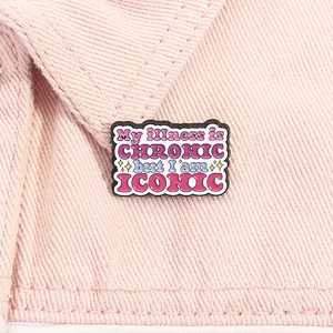 Detailed shot of an enamel brooch featuring iconic quote art on pink denim fabric