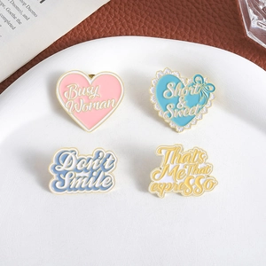 Set of 4 macaron enamel heart pins with gold edges on white plate and leather background