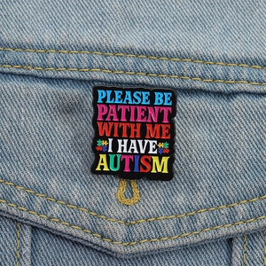 Enamel autism awareness brooch with rainbow text on denim jacket pocket