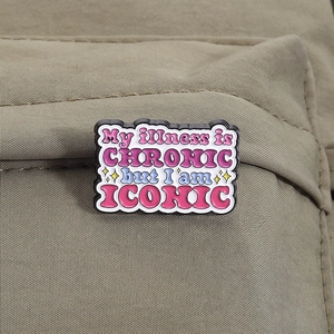 Dettaglio della spilla smaltata con citazione My illness is chronic but I am iconic su tela