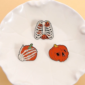 Tre spille di Halloween in smalto con teschi e zucche su un piatto di ceramica