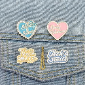 Set of 4 Sabrina Carpenter enamel pins on blue denim fabric with diverse lyrics