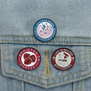 Trois pin's en émail thème café avec motifs chat et chien sur veste en jean bleue