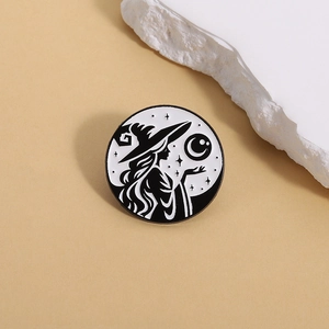 Detalle del pin esmaltado redondo en blanco y negro con una bruja y media luna