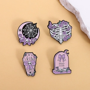 Set of four purple Gothic Halloween enamel pins with skull and coffin designs on a stone