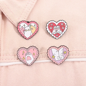 Vue détaillée de quatre épingles à chat en forme de cœur sur un tissu rose