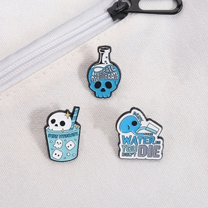 Detailed view of skull and flask enamel pins on a white canvas bag with a metal zipper