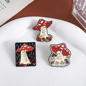 Three-piece cartoon ghost and red mushroom enamel pin set on a white ceramic plate