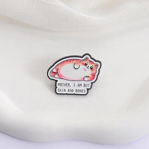 Funny fat orange cat enamel pin with Mother I Am But Skin And Bones quote on white fabric