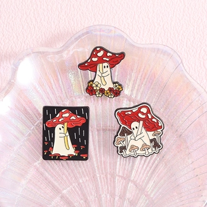 Three-piece ghost and red mushroom enamel pin set displayed on a pearl shell plate