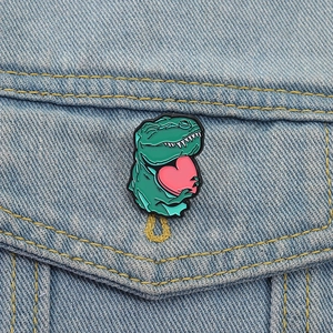 Broche en émail dinosaure T-Rex vert avec cœur rose sur poche de veste en jean