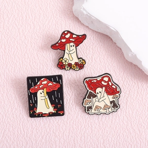 Three cute mushroom ghost enamel pins for clothes and bags on pink leather background