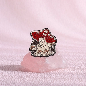 Macro shot of cartoon ghost pin sitting under a red mushroom on pink crystal