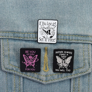 Set of three butterfly enamel pins with motivational quotes on denim jacket