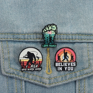 Three creative Bigfoot enamel pins set with forest and fishing themes on denim jacket