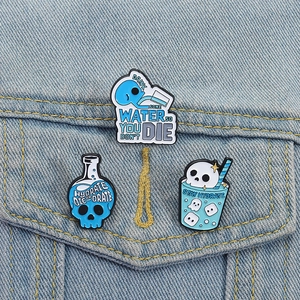 Three skeleton enamel pins set with Drink Water text on a light blue denim jacket