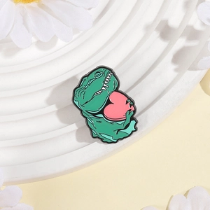 Niedliche grüne Emaille-Brosche in Dino-Form mit Herz auf floralem weißem Untergrund