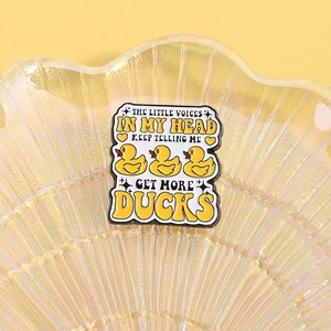 Detail of enamel duck brooch with creative text on a pearlescent decorative tray