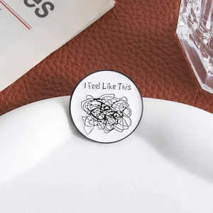 Round white enamel pin with scribble lines and I Feel Like This slogan on leather