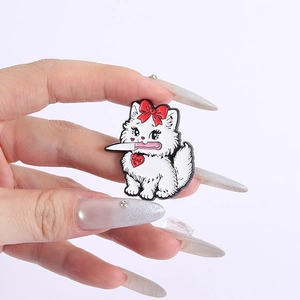 Funny white cartoon cat enamel pin with a dagger and red bow, held in hand display