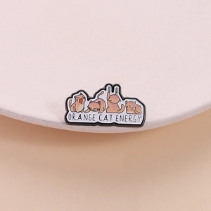 Cute enamel pin featuring orange cat illustrations with Orange Cat Energy text on a pink dish