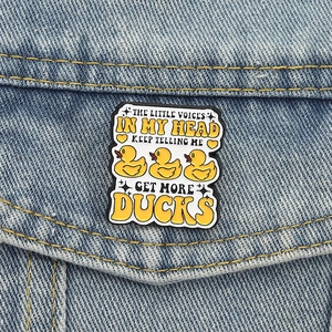 Detail of funny yellow duck enamel pin on denim jacket with creative text quote