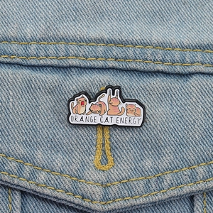 Cartoon orange cat enamel pins set featuring playful feline poses on denim jacket pocket