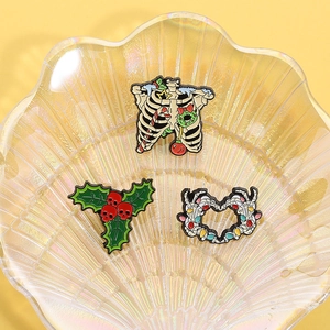 Macro detail of Halloween enamel pins featuring skulls and holly on a colorful shell tray