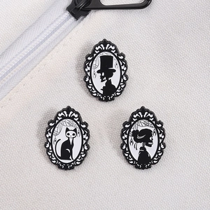 Detail of three gothic brooch pins featuring skull silhouettes in baroque frames