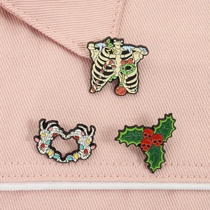 Detail of Christmas skeleton enamel pins featuring festive ribs and heart gesture