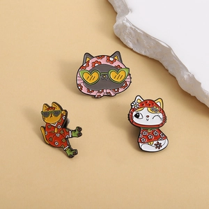 Three cute cartoon cat enamel pins with sunglasses and floral outfits on warm background