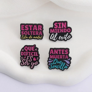 Set of four colorful Spanish quote enamel pins on a white textured display stand