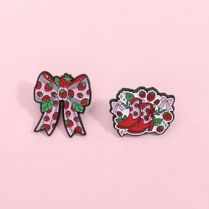Cartoon strawberry enamel pins featuring a bow and cowboy boots on a soft pink background