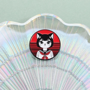 Detailed close-up of a cartoon sailor cat enamel pin on a pearlescent shell tray
