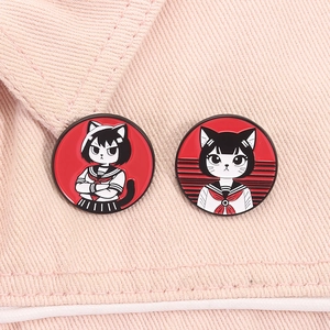 Detail of two cute sailor cat girl enamel pins on pink denim fabric background